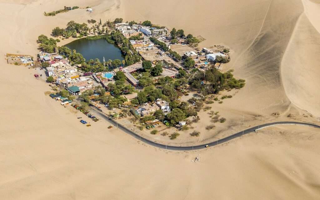 Aerial view of the Huacachina oasis surrounded by desert dunes
